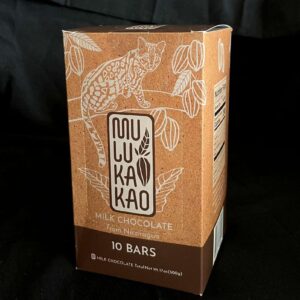 A brown box of Mukakao milk chocolate from Nicaragua, featuring a wild cat on a branch with leaves and cocoa pods, contains 10 bars totaling 17.6 oz (500 g) net weight.
