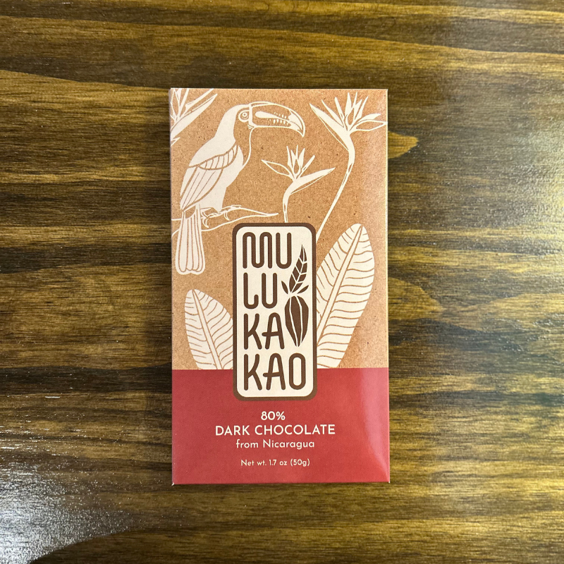 A craft chocolate bar with brown and red packaging featuring a toucan and plants, labeled “Mulu Kakao 80% Dark Chocolate from Nicaragua,” is part of the Mulukakao Signature Boozy Bonbon Collection – 24-Piece Gift Edition.